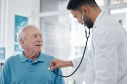 Healthcare, senior man and doctor with a stethoscope, surgeon and innovation for diagnosis, treatment and talking. Medical professional, mature male person and elderly patient with cardiology expert.