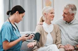 Nurse, doctor or old couple with blood pressure test consulting in hospital to monitor heart wellness. Healthcare, hypertension consultation or medical physician with a happy patient for examination.